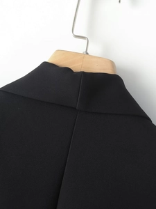 Close-up of black shawl collar stitching and fine fabric texture on a wooden hanger