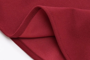 Detailed close-up of dark red fabric showing precision stitching and knit texture