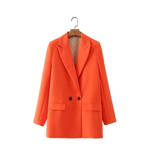 Detail view of double-breasted orange blazer with notched lapel and flap pockets