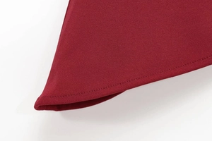 Close-up of dark red garment hem with precise double-needle stitching and textured fabric
