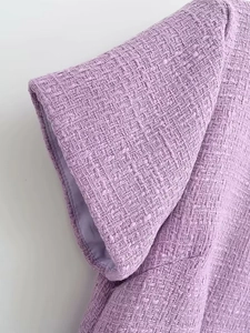 Gros plan sur le tissu en tweed violet élégant montrant la texture tissée et l'épaule