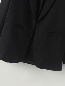 Detailed view of the black shawl collar blazer featuring smooth fabric and neat pocket stitching