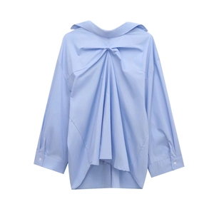 Detail of light blue oversized shirt featuring front twist knot and draped pleats