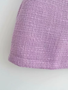Gros plan sur la texture du tweed lavande et les coutures précises de l'ourlet de la robe