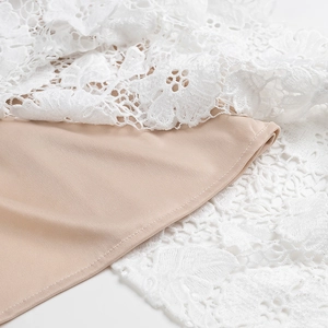 Dettaglio del ricamo in pizzo bianco con delicati motivi floreali e trama traforata