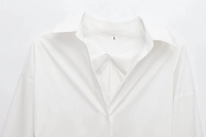 Close-up of lapel collar and shoulder seam detail on a white long-sleeve cotton shirt