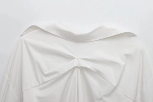 Detailed view of the back pleats and collar on this white long-sleeved shirt for women