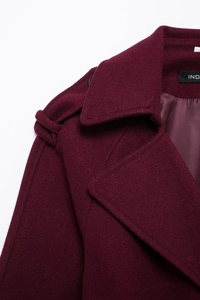 Detail shot of burgundy wool coat showing double lapel, shoulder tabs and silky lining