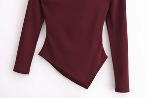 Detail des burgunderroten Stretch-Tops mit asymmetrischem Saum und feiner Strickstruktur