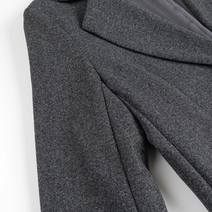 Dettaglio del cappotto di lana grigio antracite con cuciture fini e trama di tweed spessa