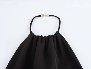 Detail des schwarzen Neckholder-Ausschnitts mit Plisseestoff und rechteckiger Goldschnalle