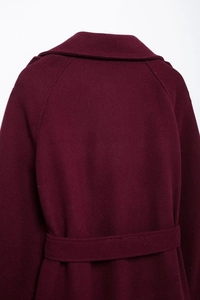 Detail view of the back of a burgundy wool coat featuring a wide collar and matching waist belt