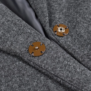 Dettaglio del cappotto di lana grigio con bottoni automatici e fodera in seta