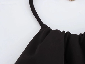 Detailaufnahme der schwarzen Kleid-Schultergurte mit eleganter Plissierung und Webstoff