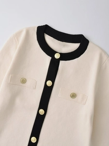 Dettaglio del cardigan in maglia con bordi a contrasto e bottoni dorati a rilievo