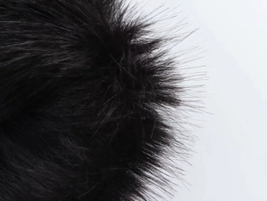 Makro-Detail von hochwertiger schwarzer Kunstpelz-Textur am Saum eines Modekleides