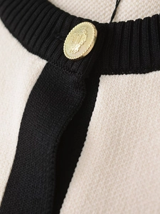 Dettaglio del bottone dorato goffrato su cardigan in maglia a contrasto chic