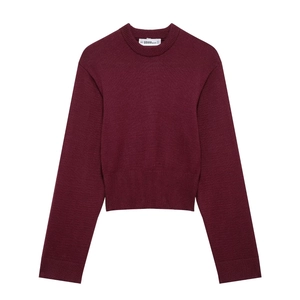 Detail of burgundy crewneck knit sweater with ribbed cuffs and interior brand label