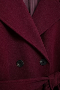 Detail of burgundy wool coat showing double-breasted marble buttons and waist belt texture