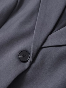 Detail of dark grey twill vest showing the lapel collar and matte black button close-up