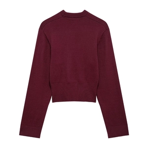 Detail view of burgundy knitted sweater featuring a ribbed crew neck and textured fabric