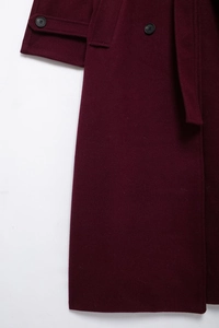 Close-up of burgundy wool blend coat featuring elegant waist belt and dark round buttons