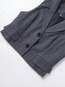 Close-up of charcoal grey sleeveless vest featuring notch lapels and flap pocket details