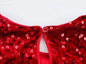 Detail of red velvet fabric with sequins and a button closure on a women's dress