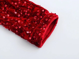 Detail of red velvet fabric with shimmering sequins on the sleeve of a party dress