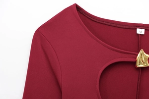 Détail d'une robe bordeaux présentant une découpe sur la poitrine et boucle dorée