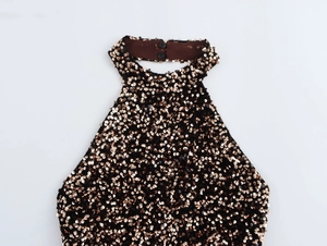 Detail of rose gold sequins on a black halter neck dress with two button back closure