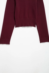 Close-up of ribbed cuffs and hem on a deep red long-sleeved flat knit sweater