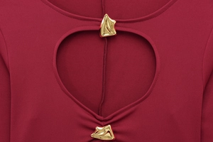 Détail de robe rouge avec découpe cœur et boucles métalliques dorées géométriques