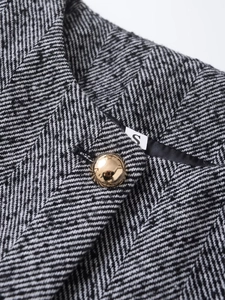 Detail of herringbone tweed fabric with premium gold-tone button and size S label