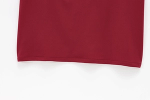 Gros plan sur l'ourlet de la robe rouge vin montrant les coutures et la texture du tissu