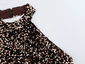 Close-up of sparkling rose gold sequins and smooth velvet fabric with button detail