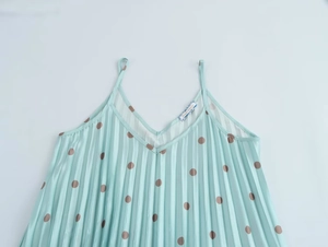 Détail du tissu plissé vert menthe à pois bruns sur une robe caraco à col en V