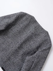 Detailed close-up of premium black and white herringbone tweed fabric texture on jacket