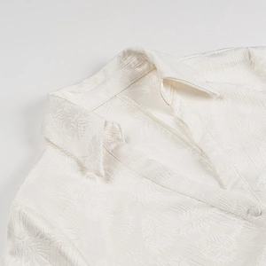 Nahaufnahme der weißen Jacquard-Stoffstruktur mit Blattmustern und feinen Nähten