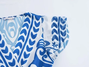 Dettaglio dello scollo a V su abito in chiffon a fiori blu con etichetta tessuta