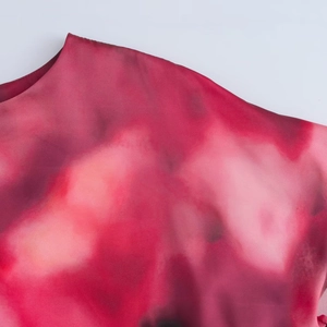 Dettaglio ravvicinato della stampa tie-dye rossa e rosa su tessuto di seta da donna
