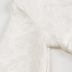Detailaufnahme der weißen Langarmbluse mit strukturierter Blatt-Jacquard-Webung