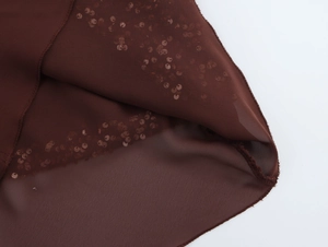 Macro shot of brown sequined chiffon fabric with shimmering dots and elegant drape