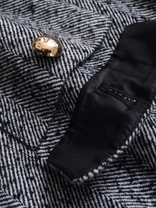 Close-up of golden metal button on herringbone tweed jacket with premium stitching