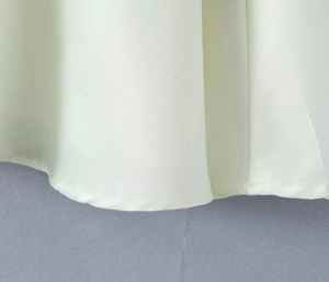 Vue détaillée de l'ourlet d'une robe française à col en V en tissu tissé lisse et soyeux