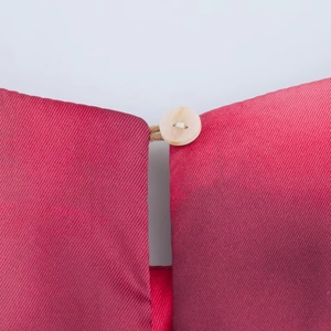 Dettaglio macro del tessuto twill rosso e del bottone bianco sull'abito di raso a fiori