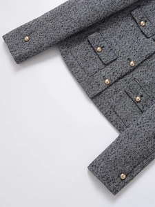 Detail of herringbone tweed fabric and golden metal buttons on classic jacket