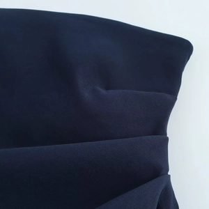 Gros plan détaillé sur le tissu plissé bleu marine et la texture drapée de ce haut chic
