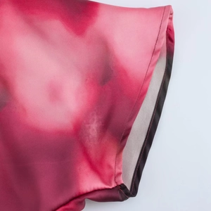 Dettaglio di un abito in seta con motivo sfumato tie-dye rosso e rosa e bordi rifiniti