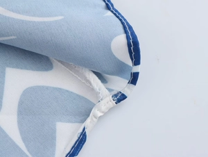 Detailed close-up showing the blue and white floral print fabric with rolled hem stitching